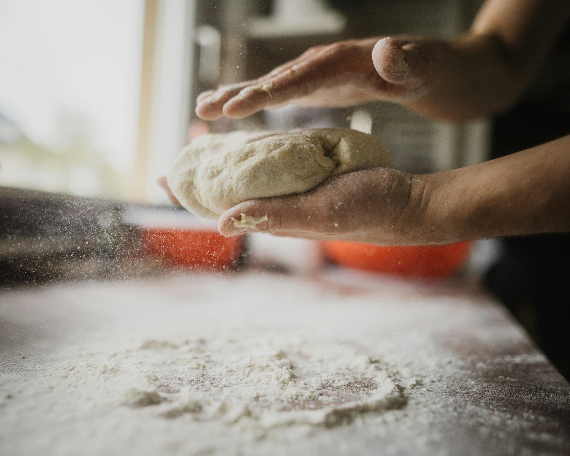 Hands kneading dough with flour dusting a surface, perfect for a corporate cooking class team building