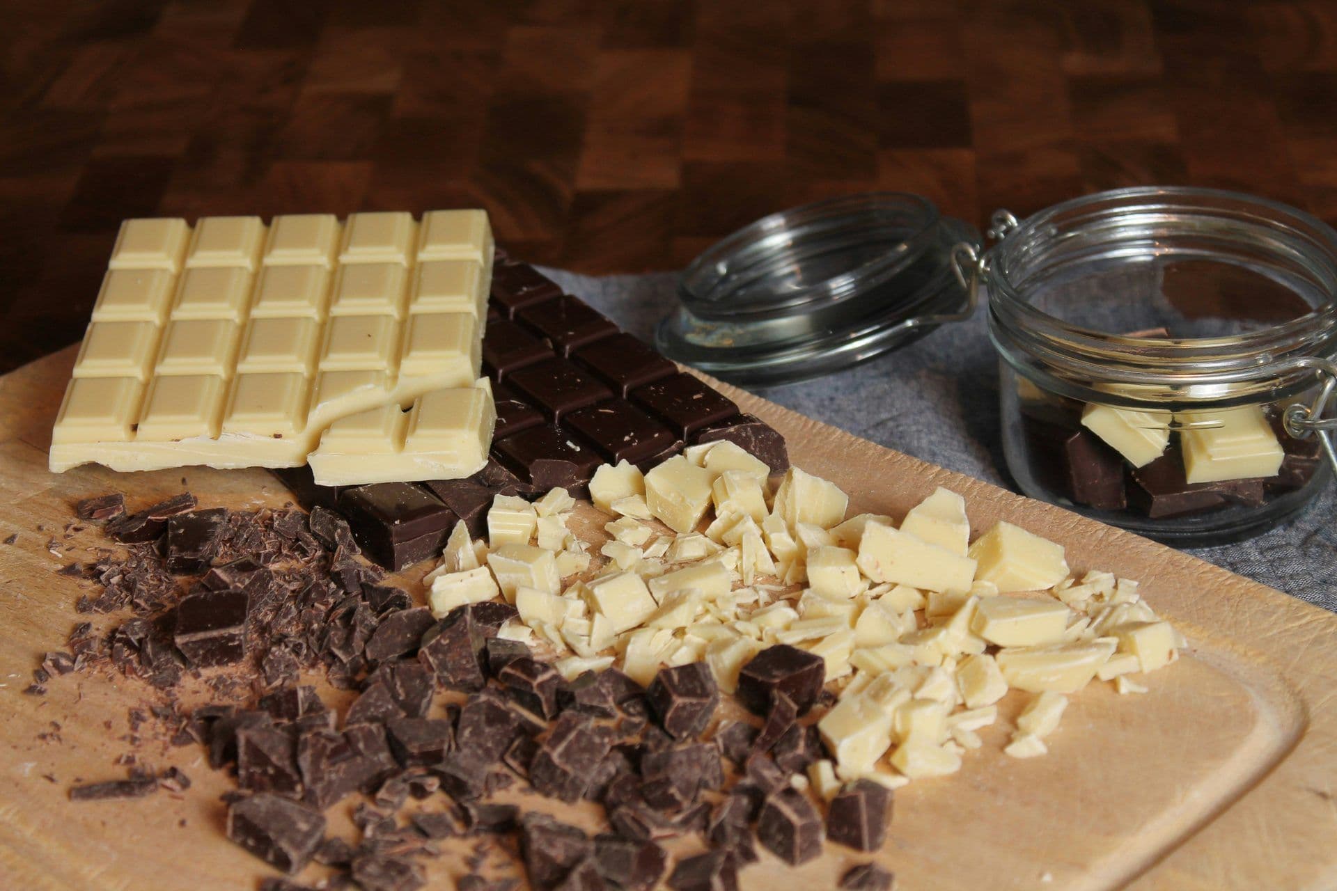 White and dark chocolate bars and chopped pieces on a wooden board, ready for a corporate cooking class.