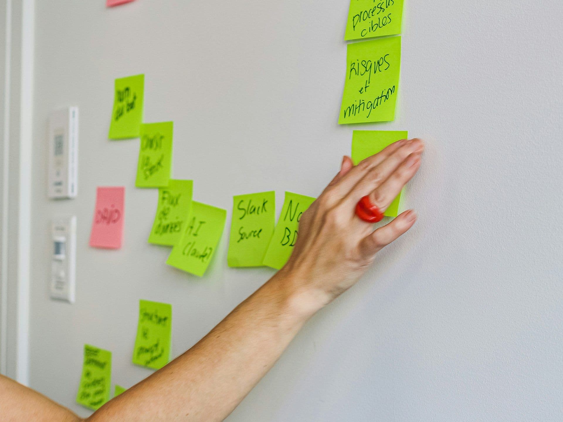 A participant's hand places a green sticky note on a wall during a team building workshop.