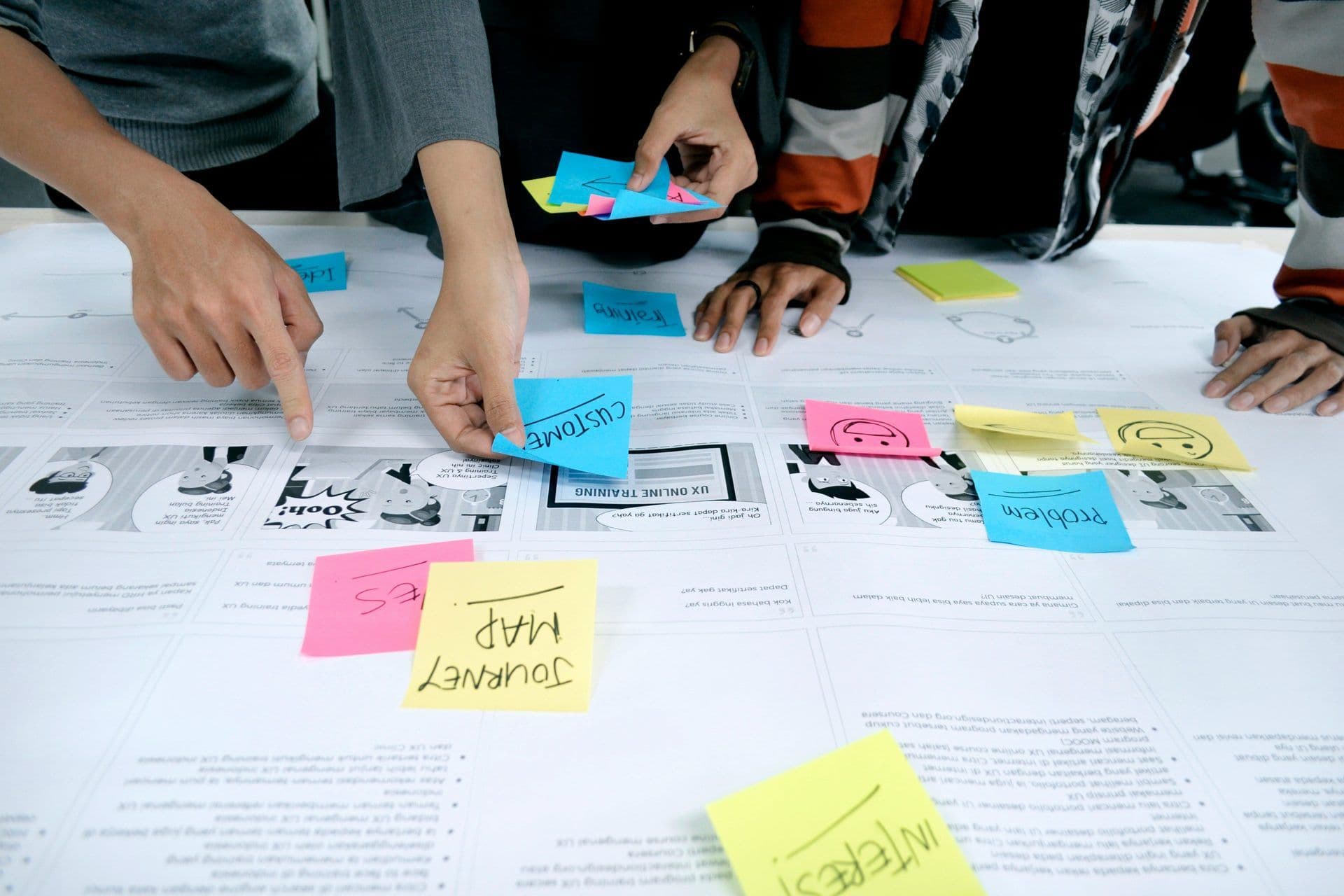 Hands placing colorful sticky notes on a large diagram during a collaborative corporate workshop in Indonesia.
