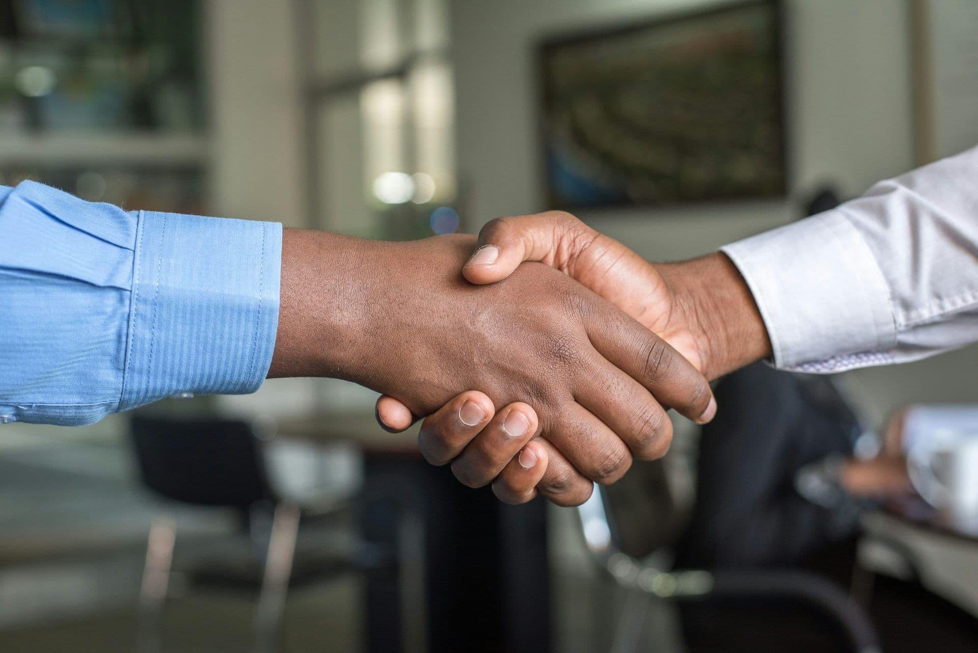 Close-up of two professionals shaking hands, representing collaboration at a corporate event or meeting.