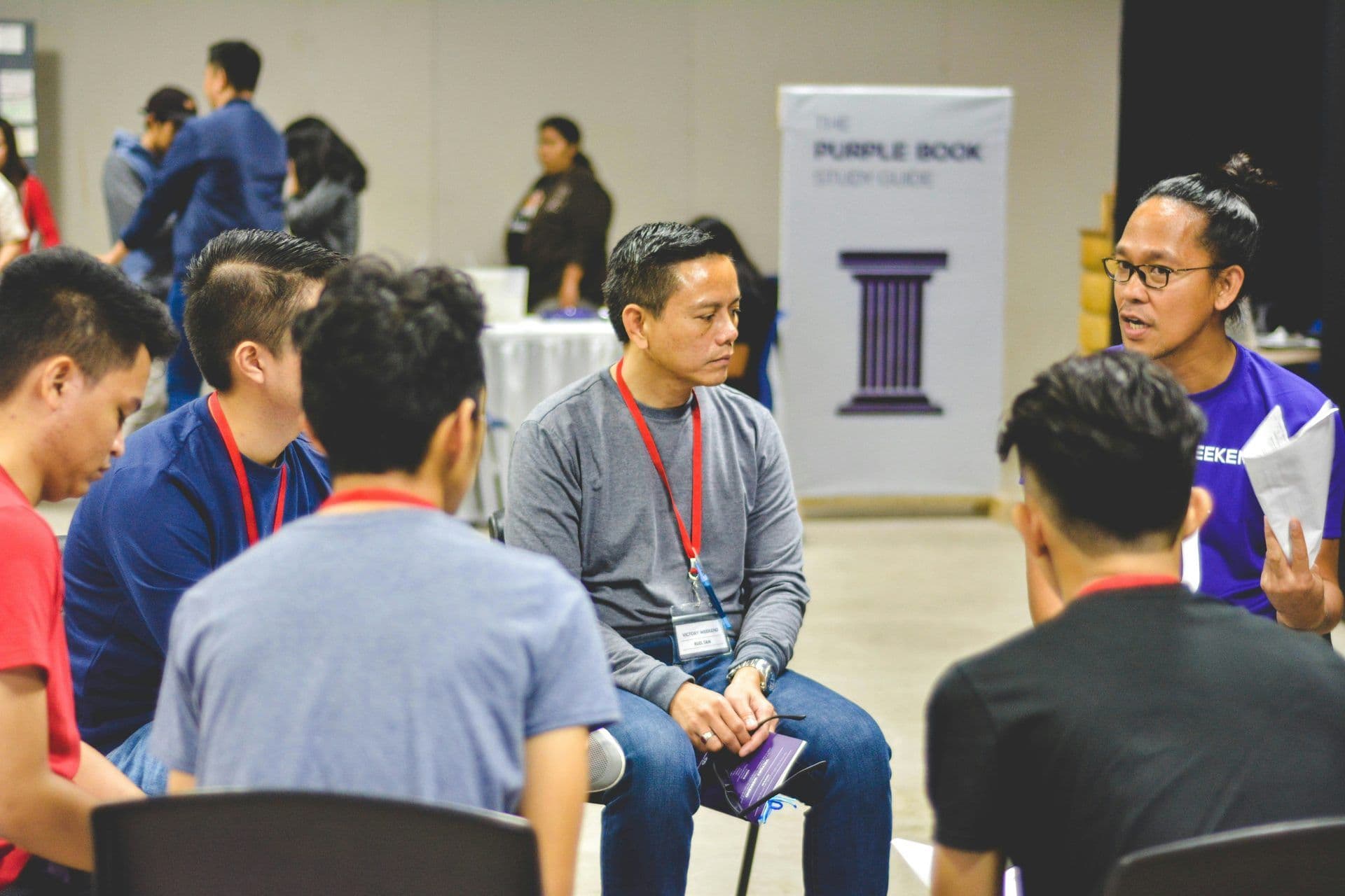 Attendees at a corporate seminar actively participate in a small group discussion in a large event space.
