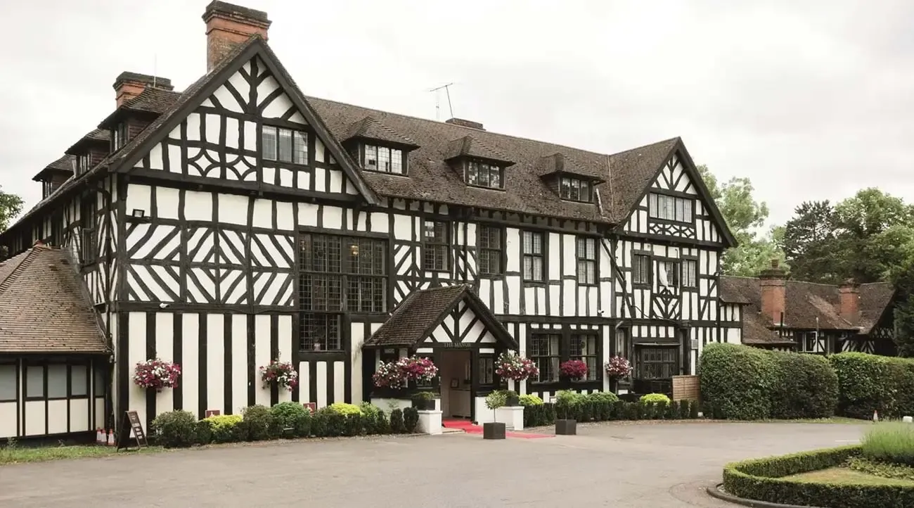 Historic black and white half-timbered manor house with a red carpet entrance, ideal for corporate events.