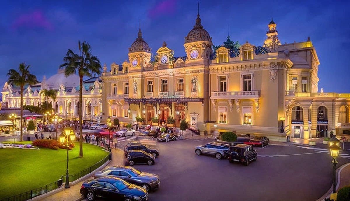 Grand historic corporate event venue in Monte Carlo, Monaco, illuminated at dusk with luxury cars.