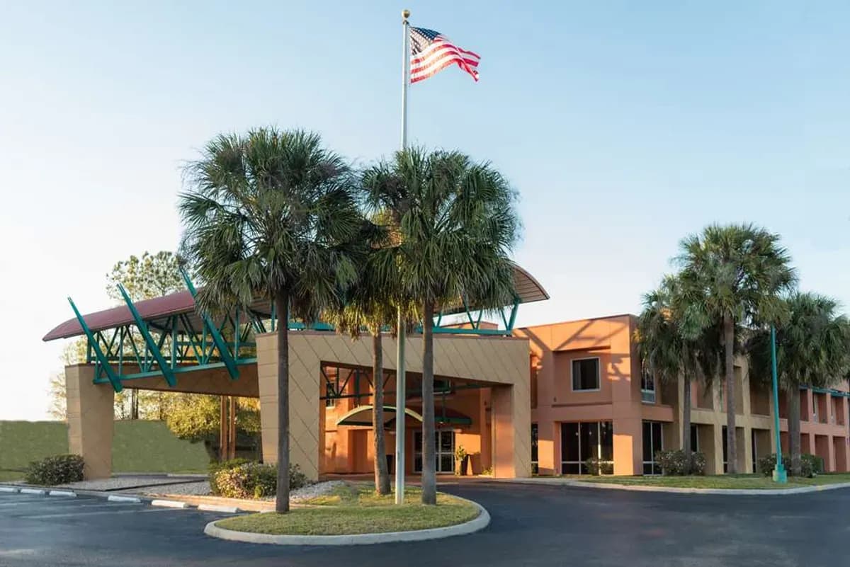 Modern corporate event venue entrance with palm trees and an American flag flying under a clear sky.