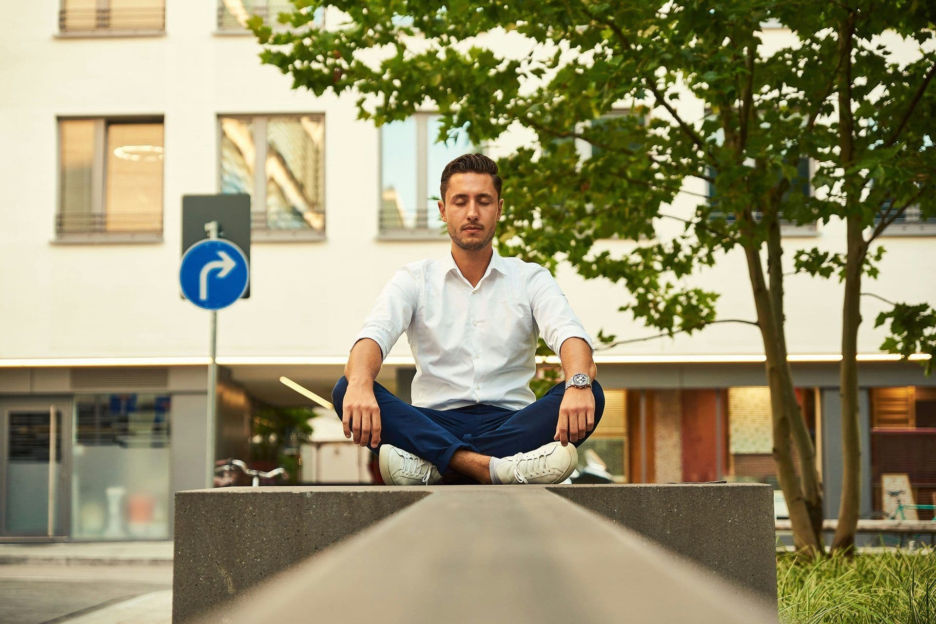 A man meditating outdoors in a city, ideal for a corporate wellness or team building activity.