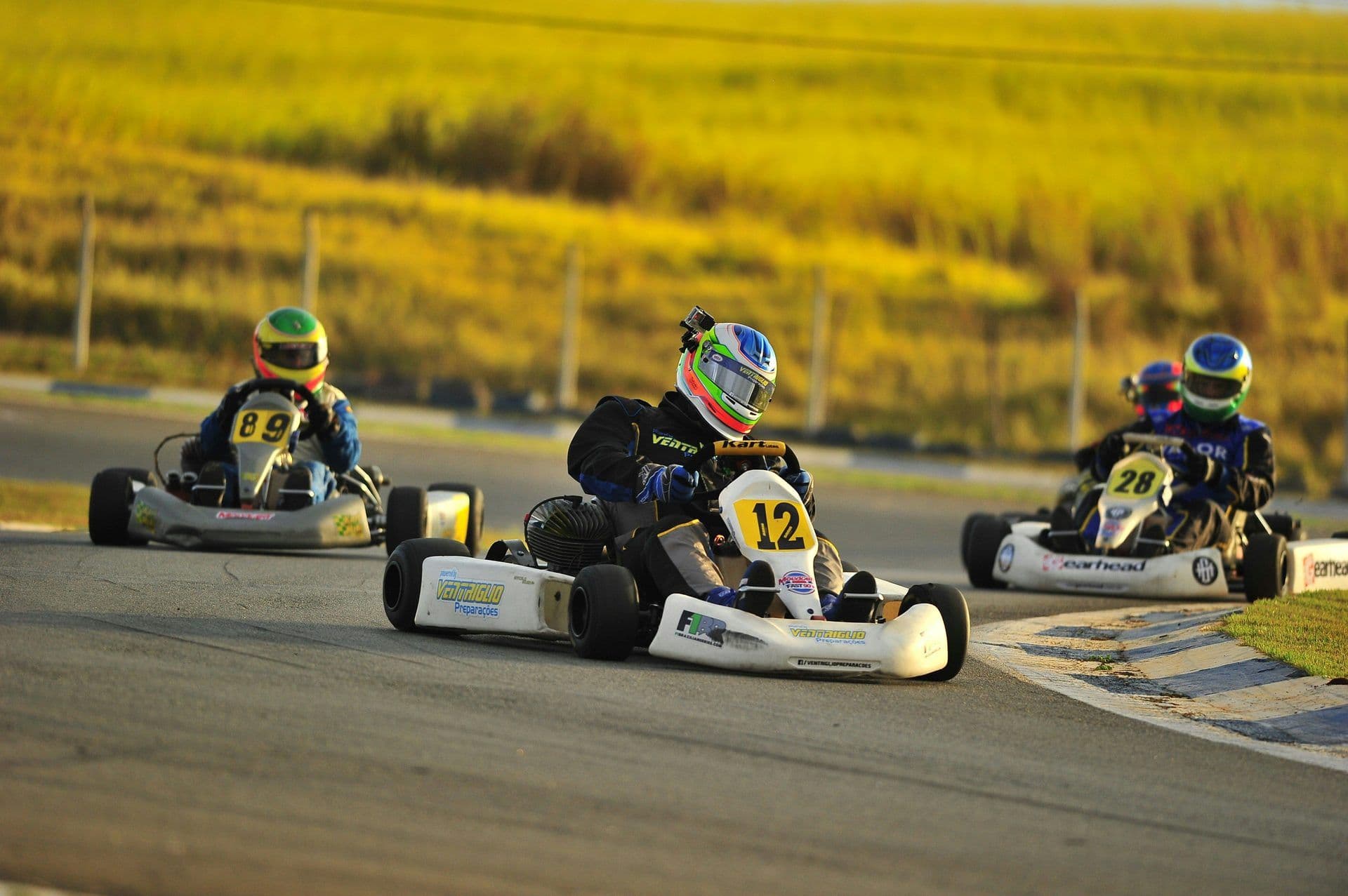 Three people in go-karts race on an outdoor track, perfect for a corporate team building activity.