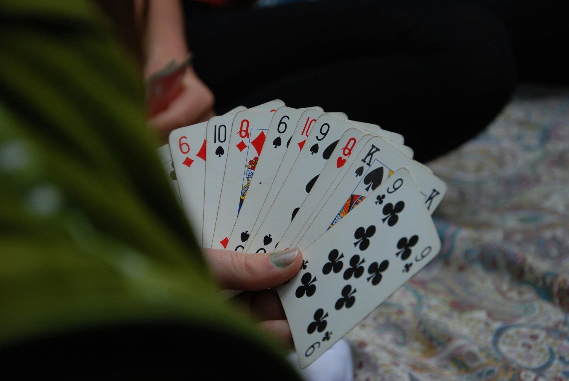 A person's hand holds a fan of playing cards, ideal for a fun team building game or corporate activity.