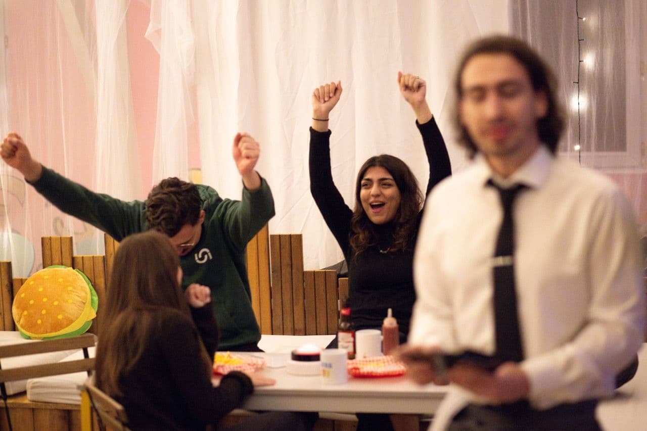 Excited employees cheer during a corporate team building quiz at a lively privatised restaurant.