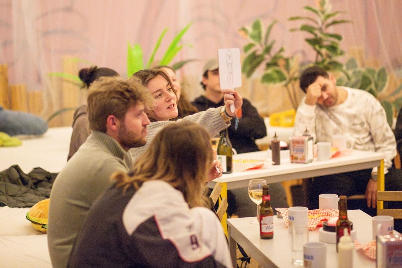 Colleagues participate in a food-themed quiz, raising paddles during a team building activity.