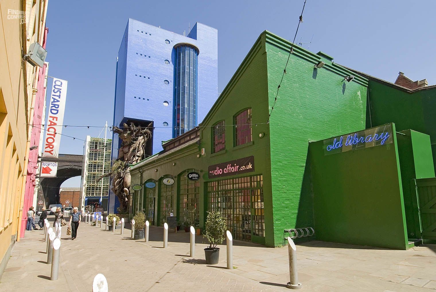 Vibrant green and blue buildings, including the Custard Factory and Old Library event space in Birmingham, UK.