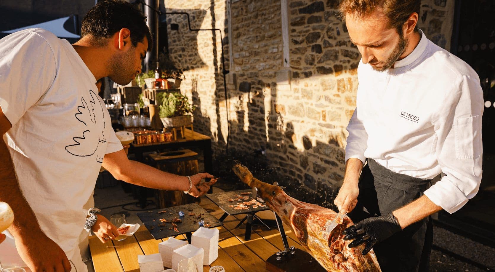 Chef carving jamón for a corporate cocktail reception at an outdoor historic venue in France.