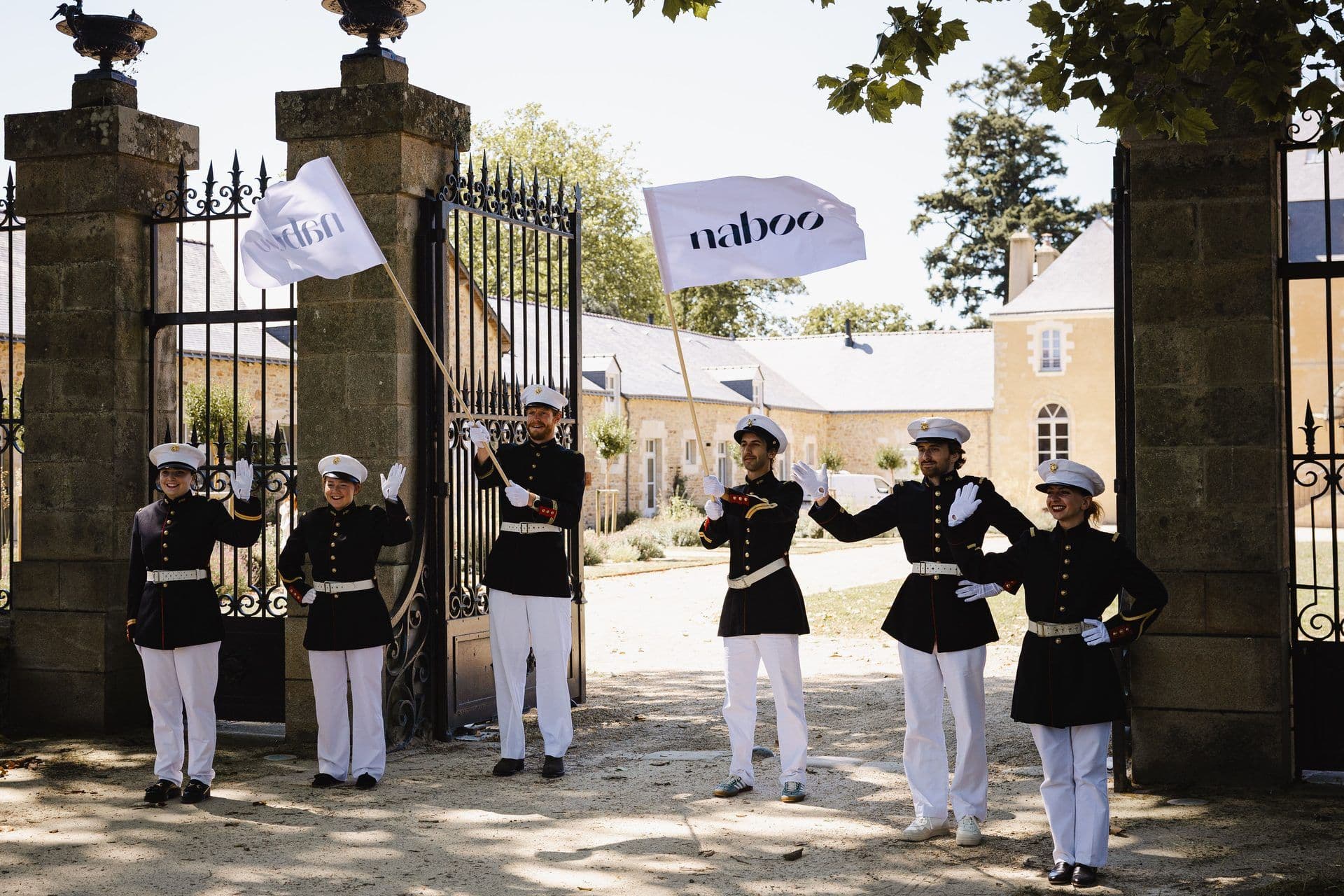 Six uniformed staff hold Naboo flags, welcoming guests at the entrance of a historic corporate event venue.