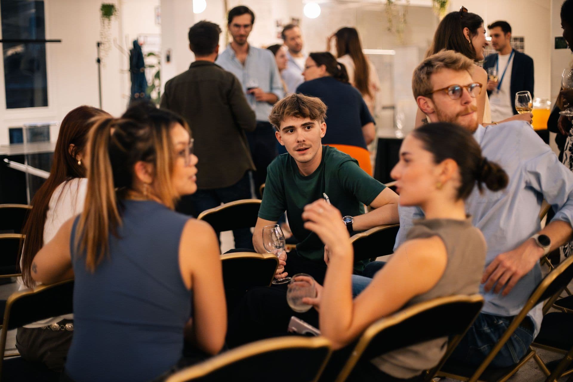 Attendees mingle with drinks at a lively corporate networking event in a modern event space.