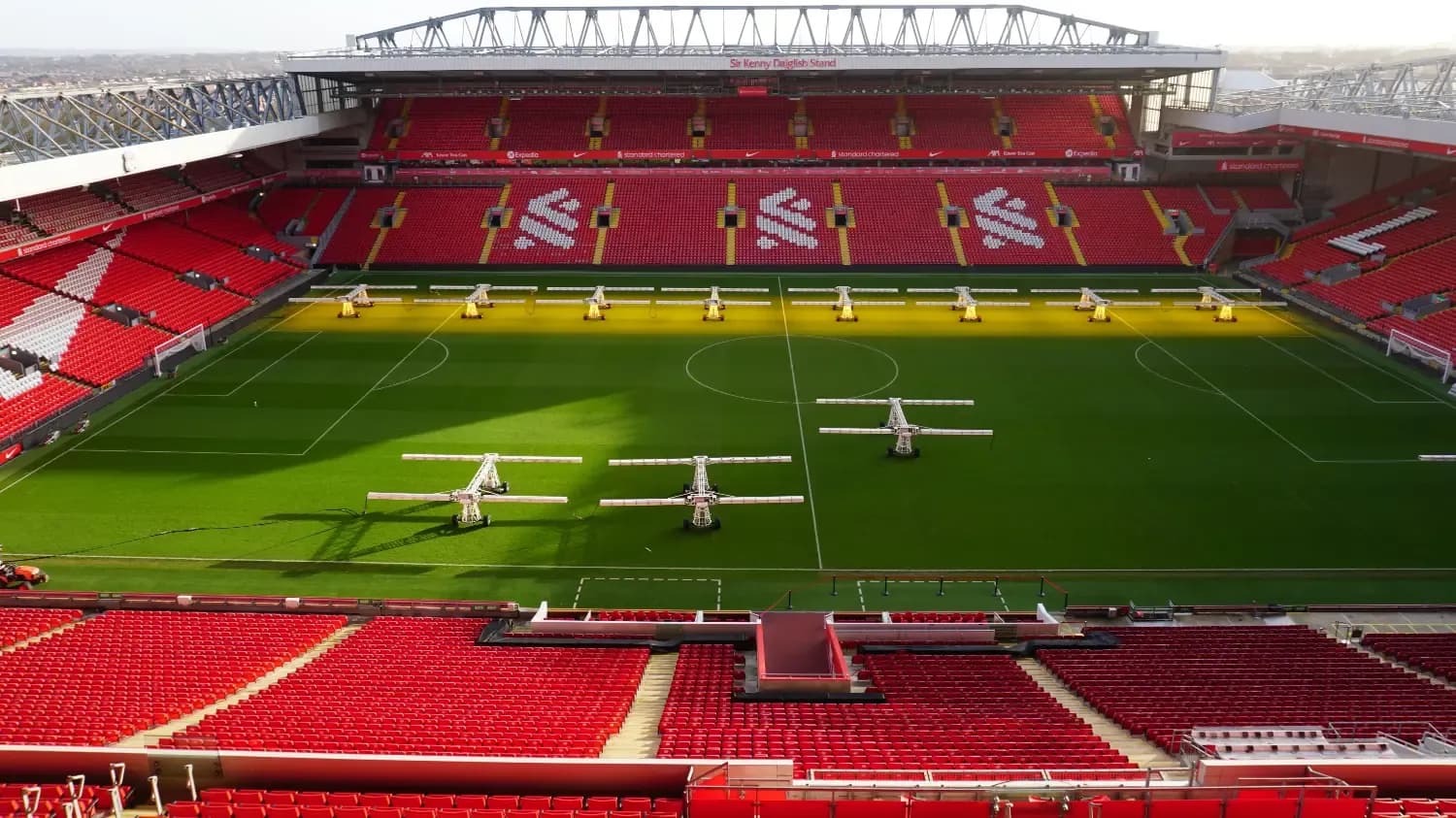 Large corporate event venue in Liverpool: an empty football stadium with red seats and pitch grow lights.