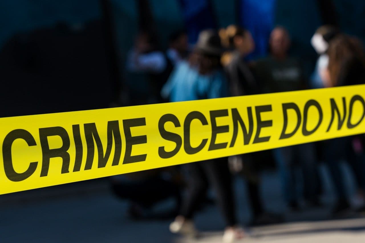 Yellow 'CRIME SCENE DO NOT CROSS' tape, hinting at an immersive murder mystery team building activity.