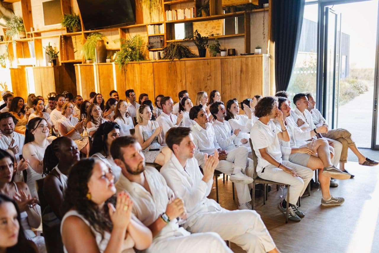 A large group of employees attending a corporate seminar, clapping in a bright, modern event space.