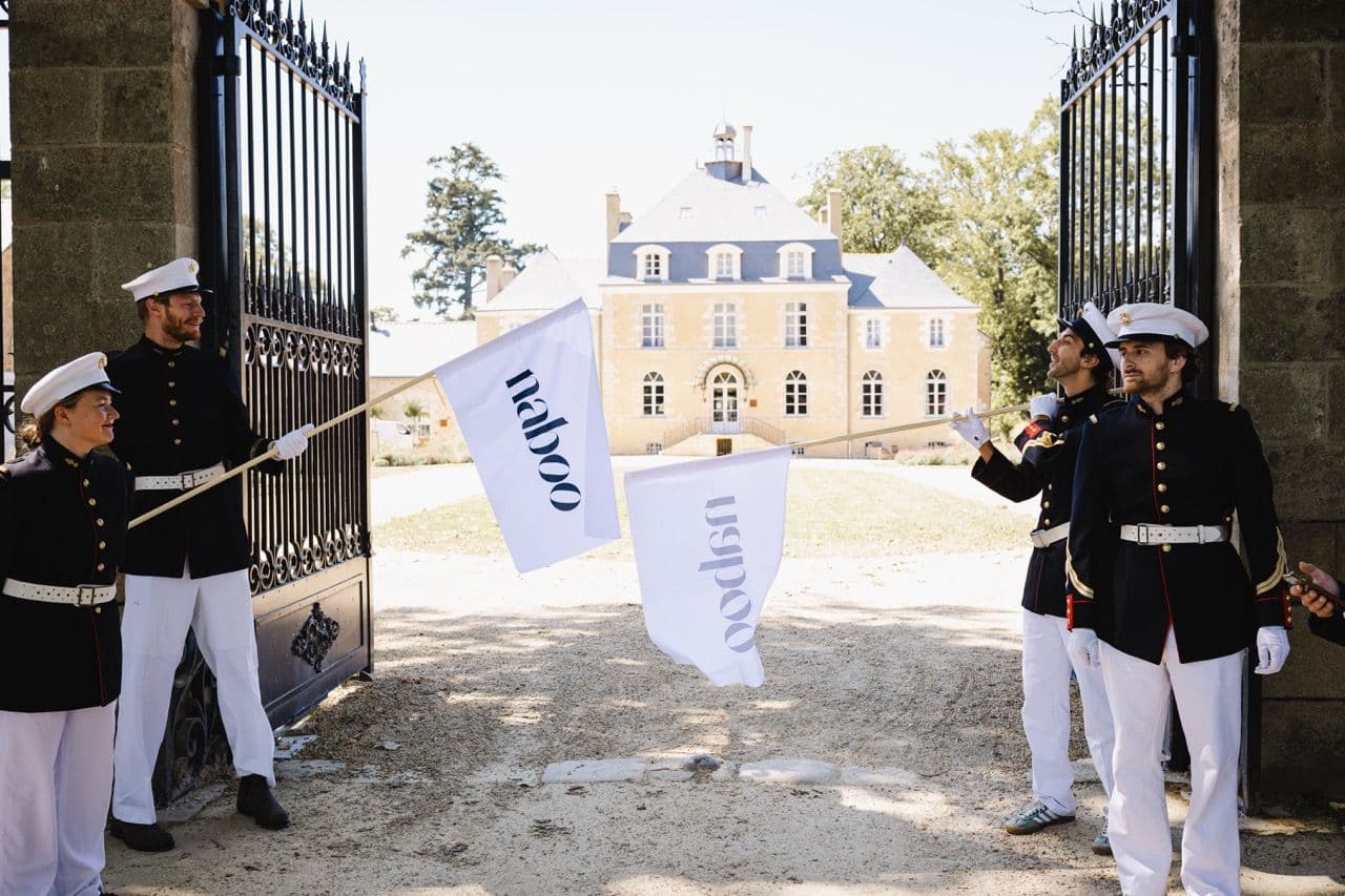 People in uniforms holding Naboo flags at the grand entrance of a historic corporate event venue.