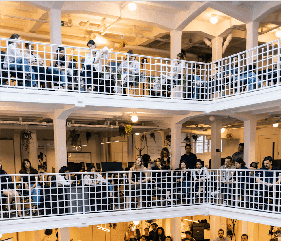Attendees gather across multiple levels of a modern, open-plan corporate event venue.
