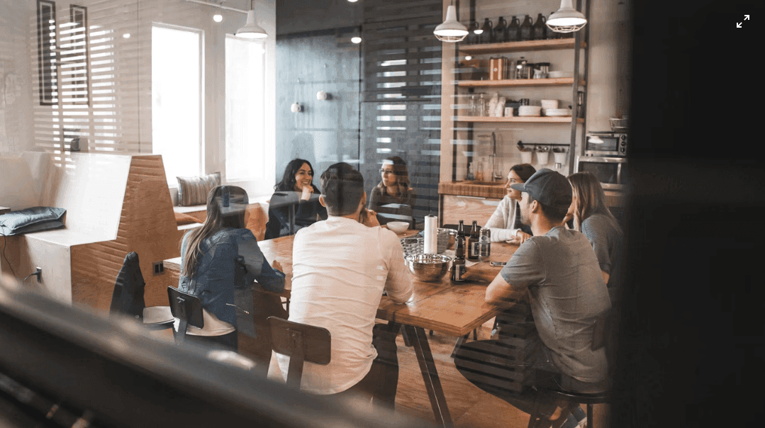 Team members collaborate around a large wooden table in a bright, modern corporate event venue.