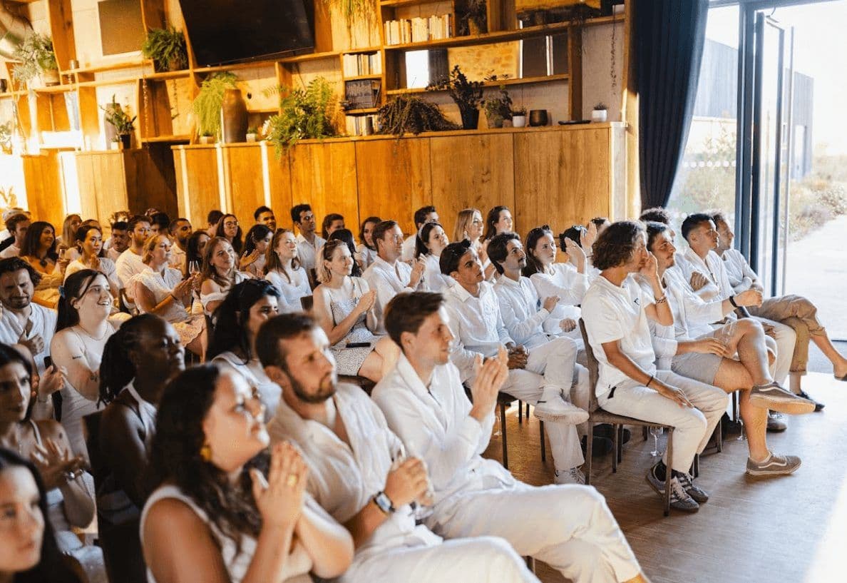 Attendees clap during a corporate seminar or team offsite in a modern event space with wooden decor.