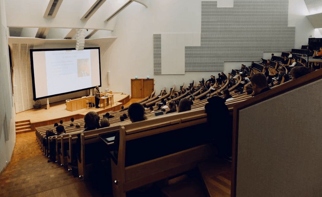 Modern auditorium venue with a speaker presenting to a large audience during a corporate seminar.