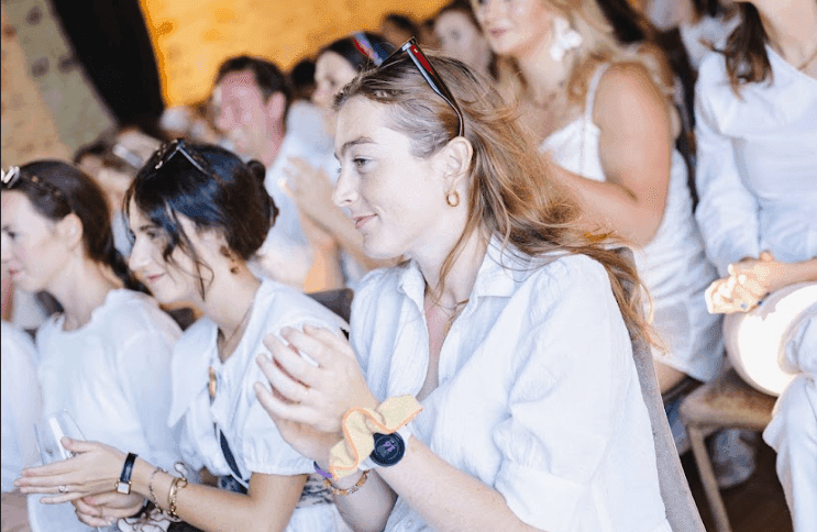 A group of engaged attendees in white shirts clapping at an indoor corporate event.