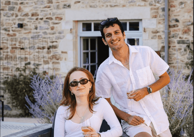 Two smiling people enjoying a wine tasting event at an outdoor historic corporate event venue.