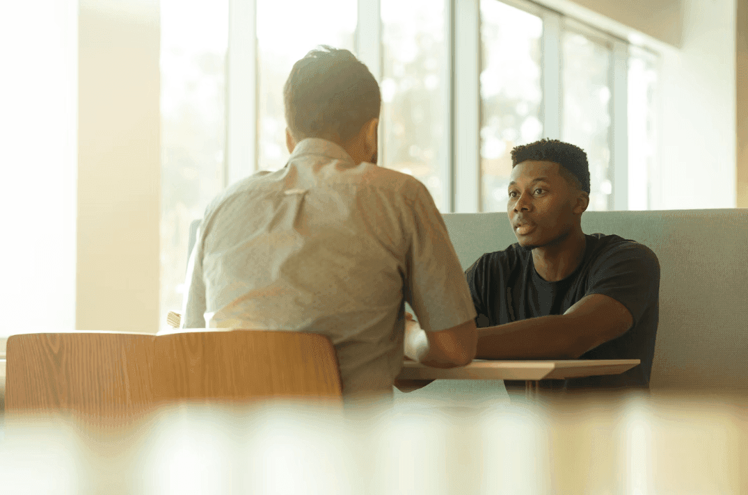 Two men having a discussion in a bright, modern meeting room, perfect for a corporate seminar.