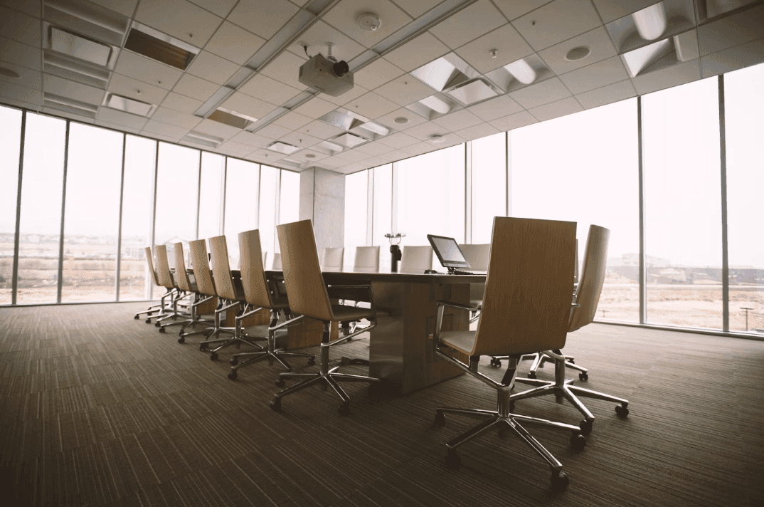 Spacious corporate event venue featuring a large boardroom table, projector, and floor-to-ceiling windows.