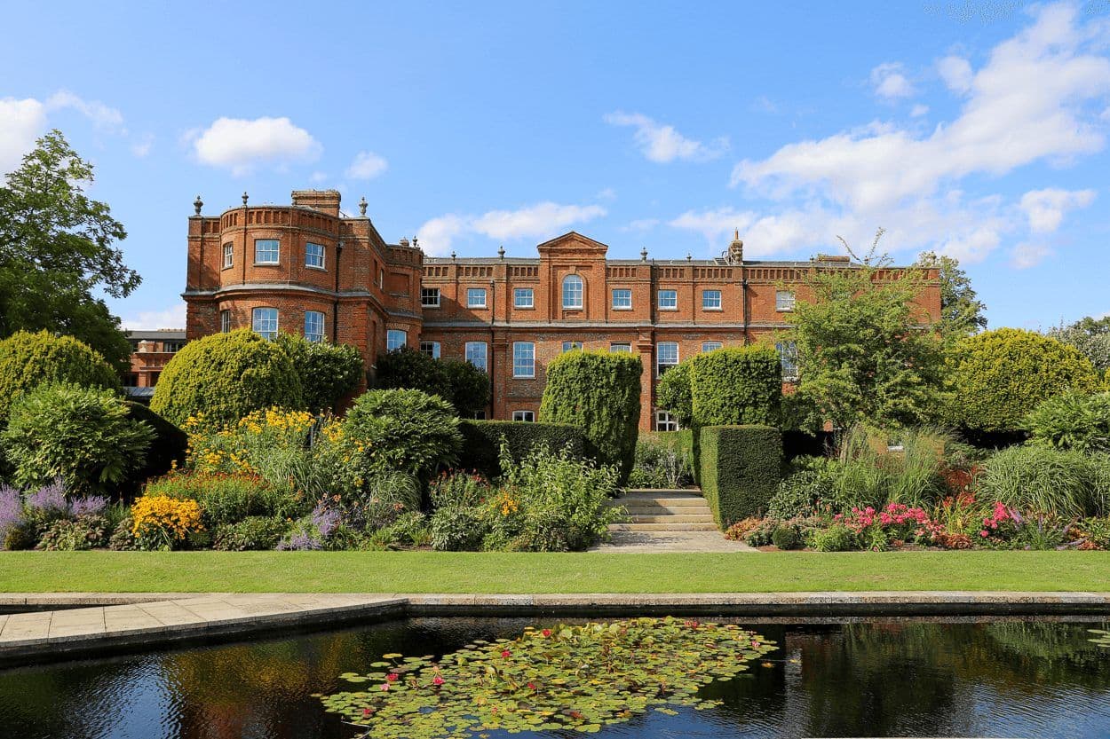 Historic red brick mansion with formal gardens and a pond in England, ideal for corporate events.