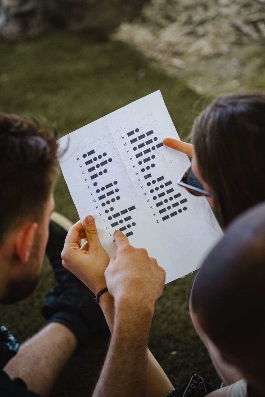 Close-up of colleagues deciphering a Morse code sheet for an escape room team building event.