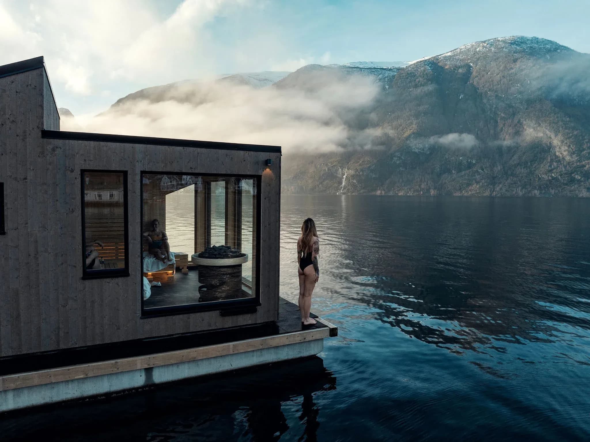 Floating wooden sauna on a serene Norwegian fjord, a unique venue for corporate retreats
