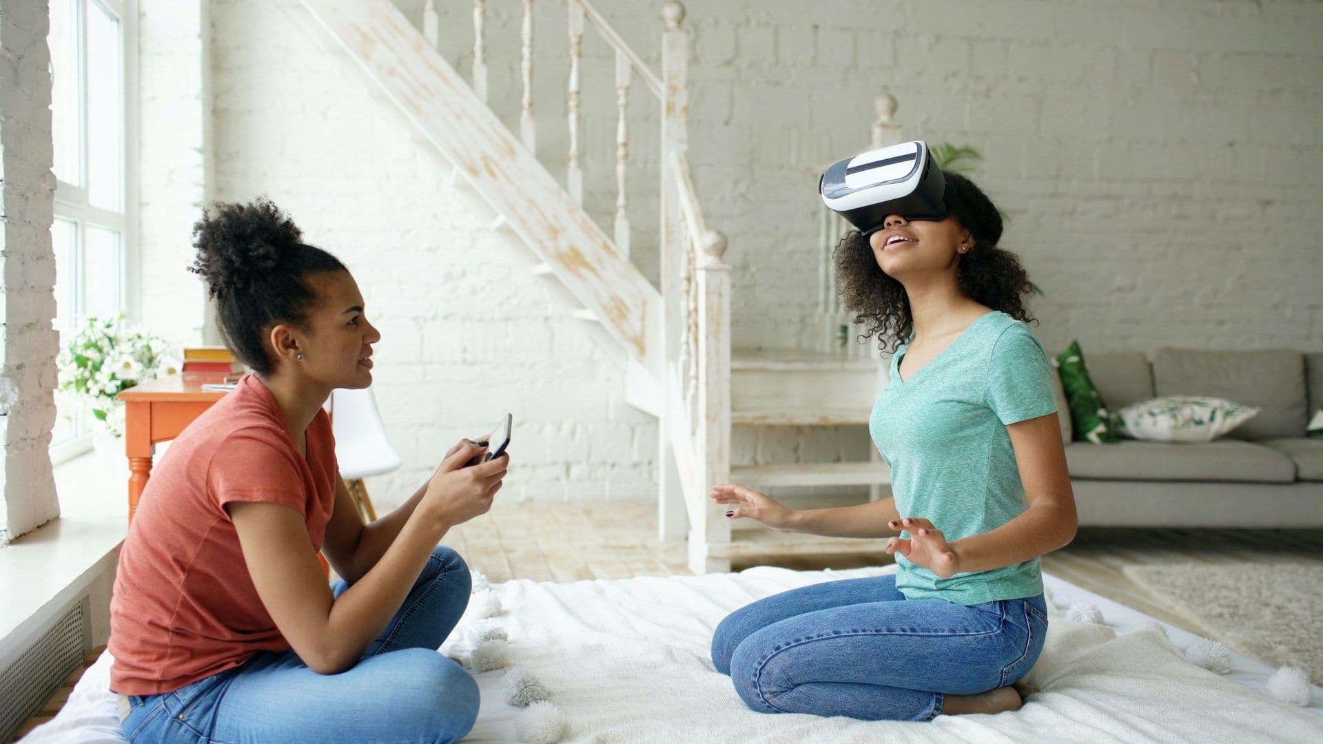Two women participate in a virtual reality team building activity in a bright, modern event space.