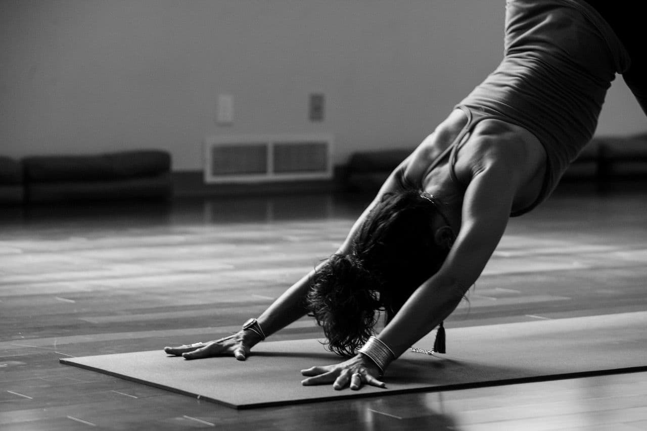 A person performing a yoga pose on a mat in a spacious room, perfect for team building or wellness retreats.