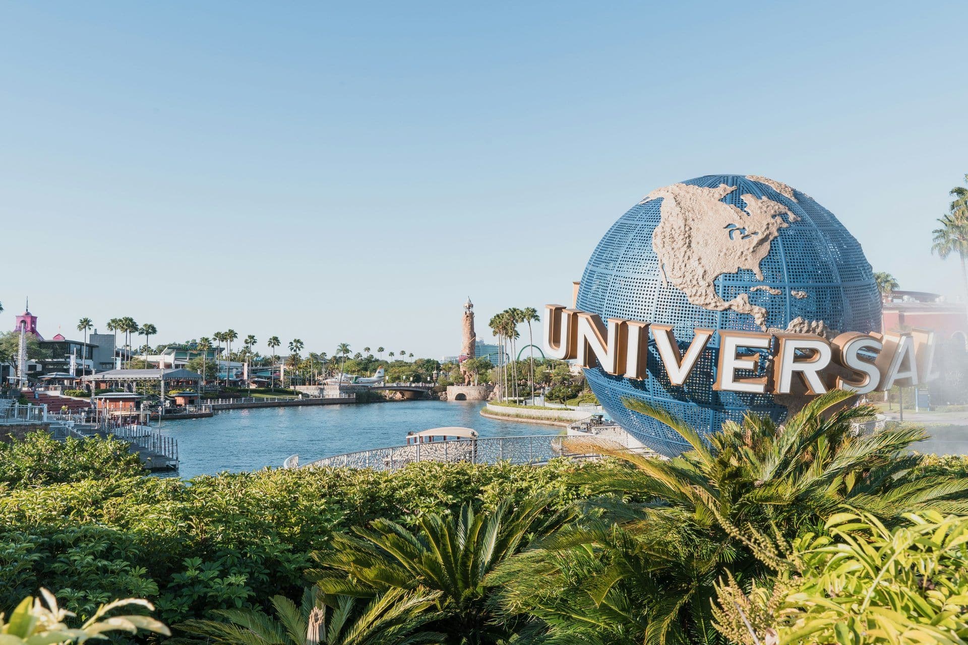 The Universal Studios globe stands prominently by a waterfront event space with palm trees in Orlando