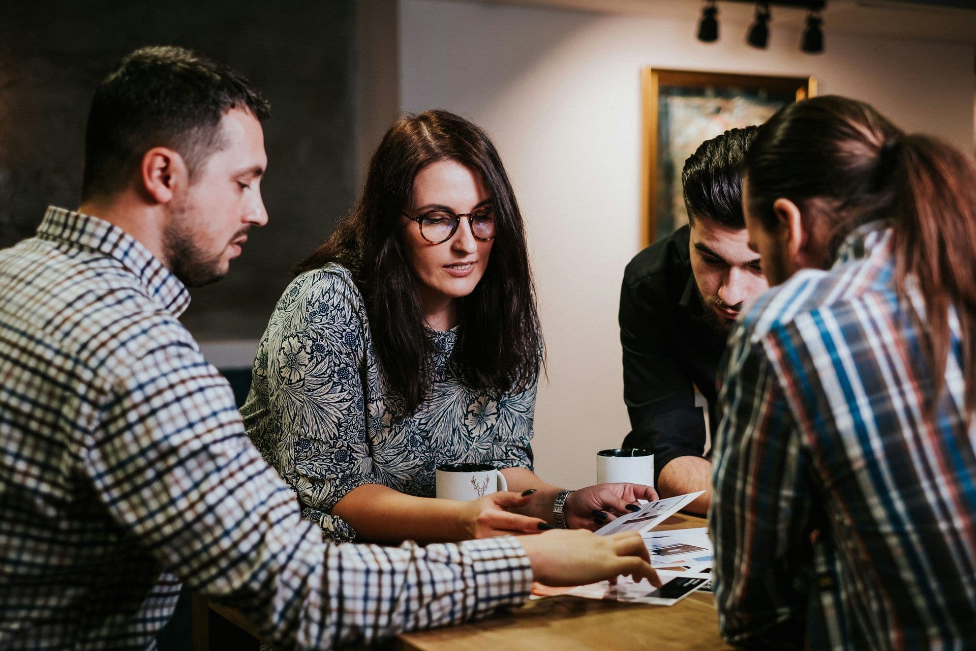 Four colleagues collaborate, reviewing documents and discussing ideas around a wooden table.