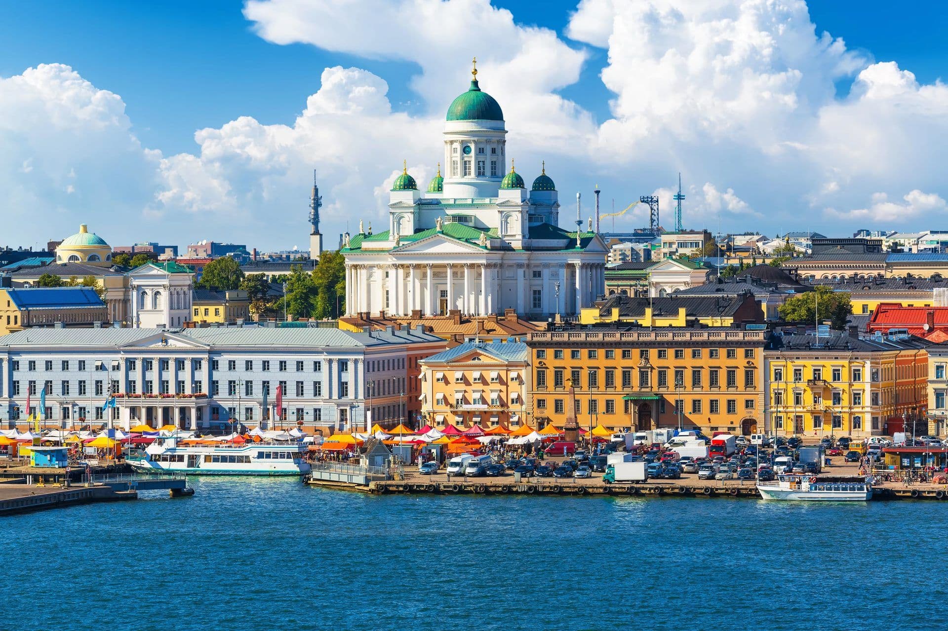 Helsinki cityscape with the iconic white cathedral, colorful market, and waterfront on a sunny day in Finland.