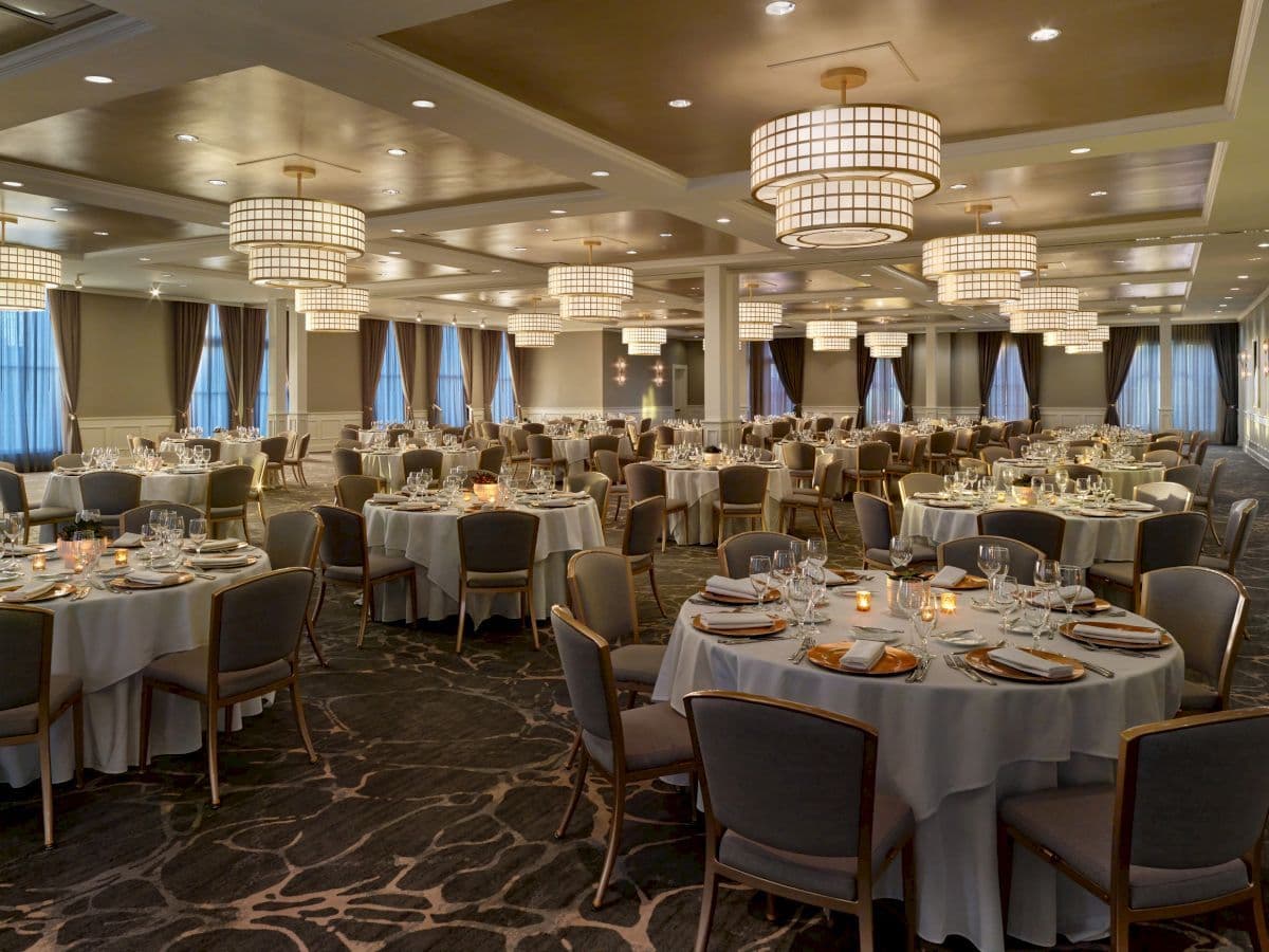 Elegant ballroom venue in Galveston, TX, set for a large corporate dinner with numerous round tables.