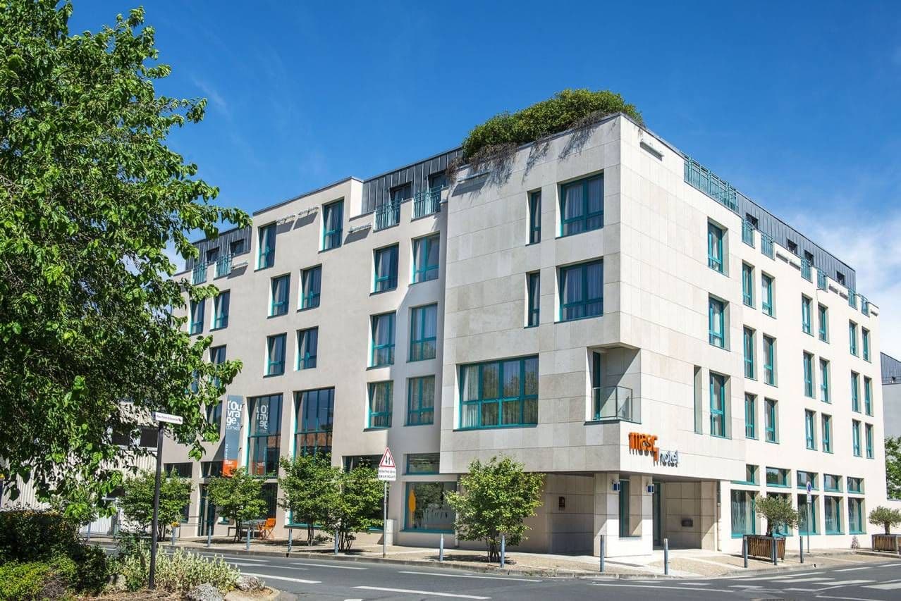 Modern Masq Hotel building, a corporate event venue, with a light facade and teal windows.