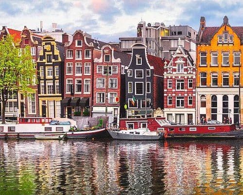 Historic canal houses and boats line a picturesque canal in Amsterdam