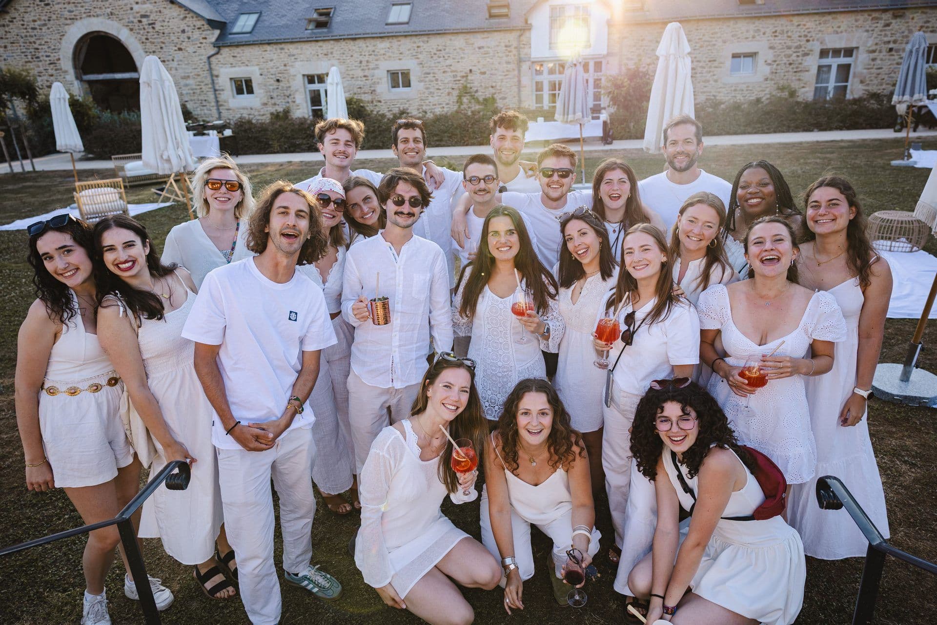 Smiling team members in white attire at an outdoor corporate event venue during a company offsite.