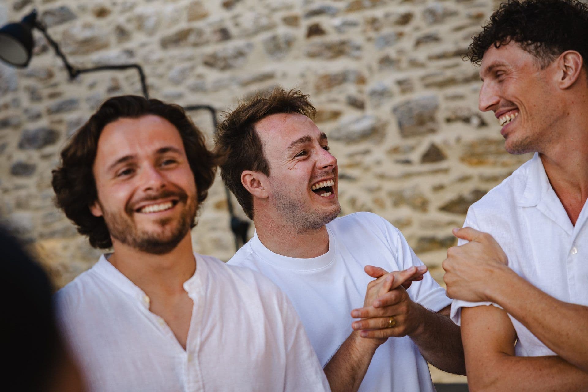 Three men laughing and clapping during a corporate team building activity at an outdoor event space.
