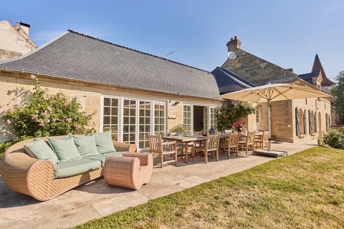 Historic stone building with a sunny outdoor terrace, dining area, and lounge seating for corporate events.