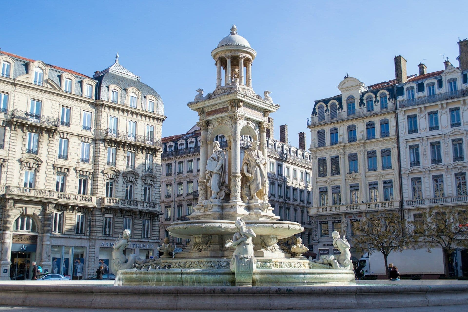 Ornate Bartholdi Fountain in a historic city square in Lyon, France, surrounded by elegant buildings.