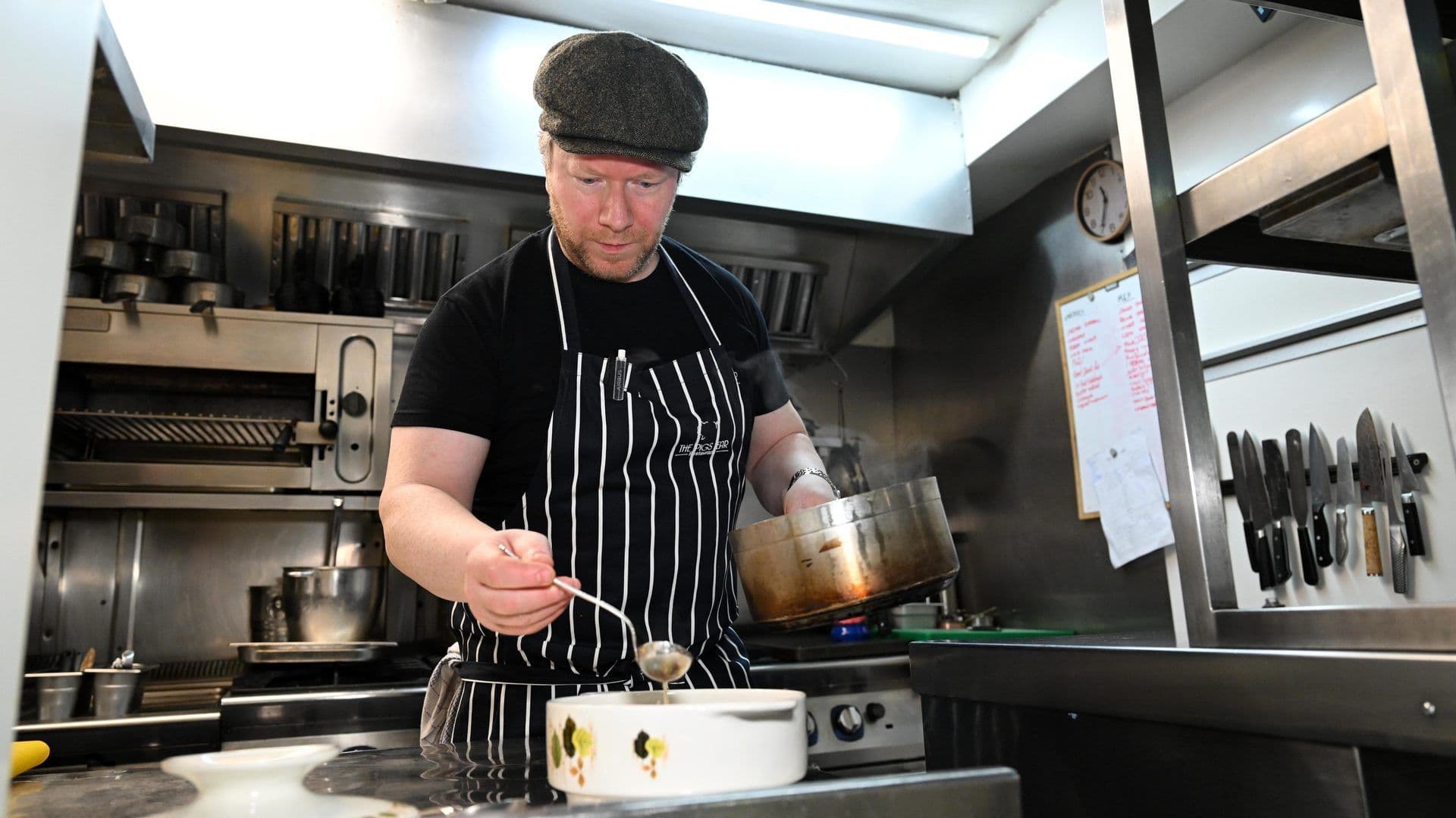 A chef in a professional restaurant kitchen ladling food, perfect for a cooking class team building.