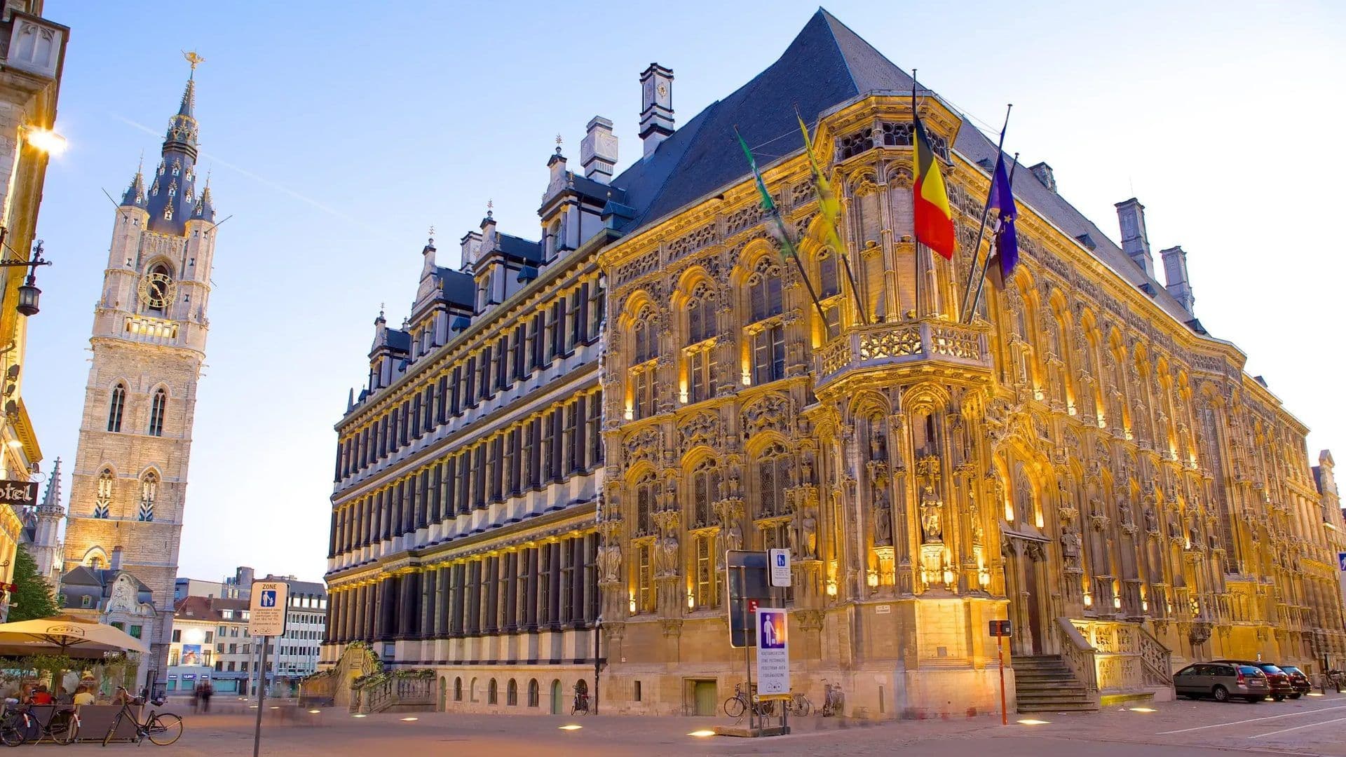 Ornate historic corporate event venue and bell tower illuminated at dusk in Ghent, Belgium.