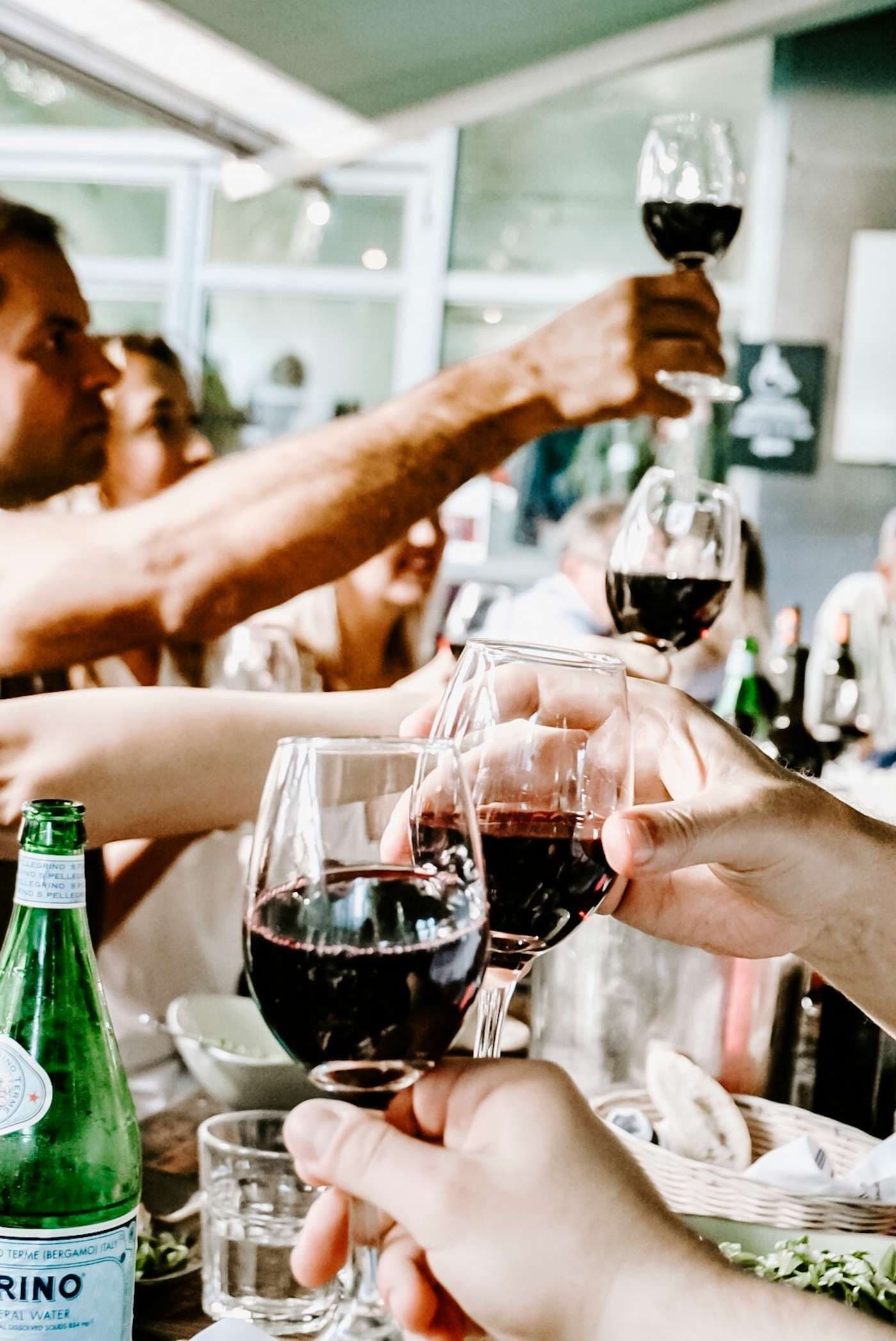 Guests clinking red wine glasses at a corporate dinner or networking event in a private dining room.