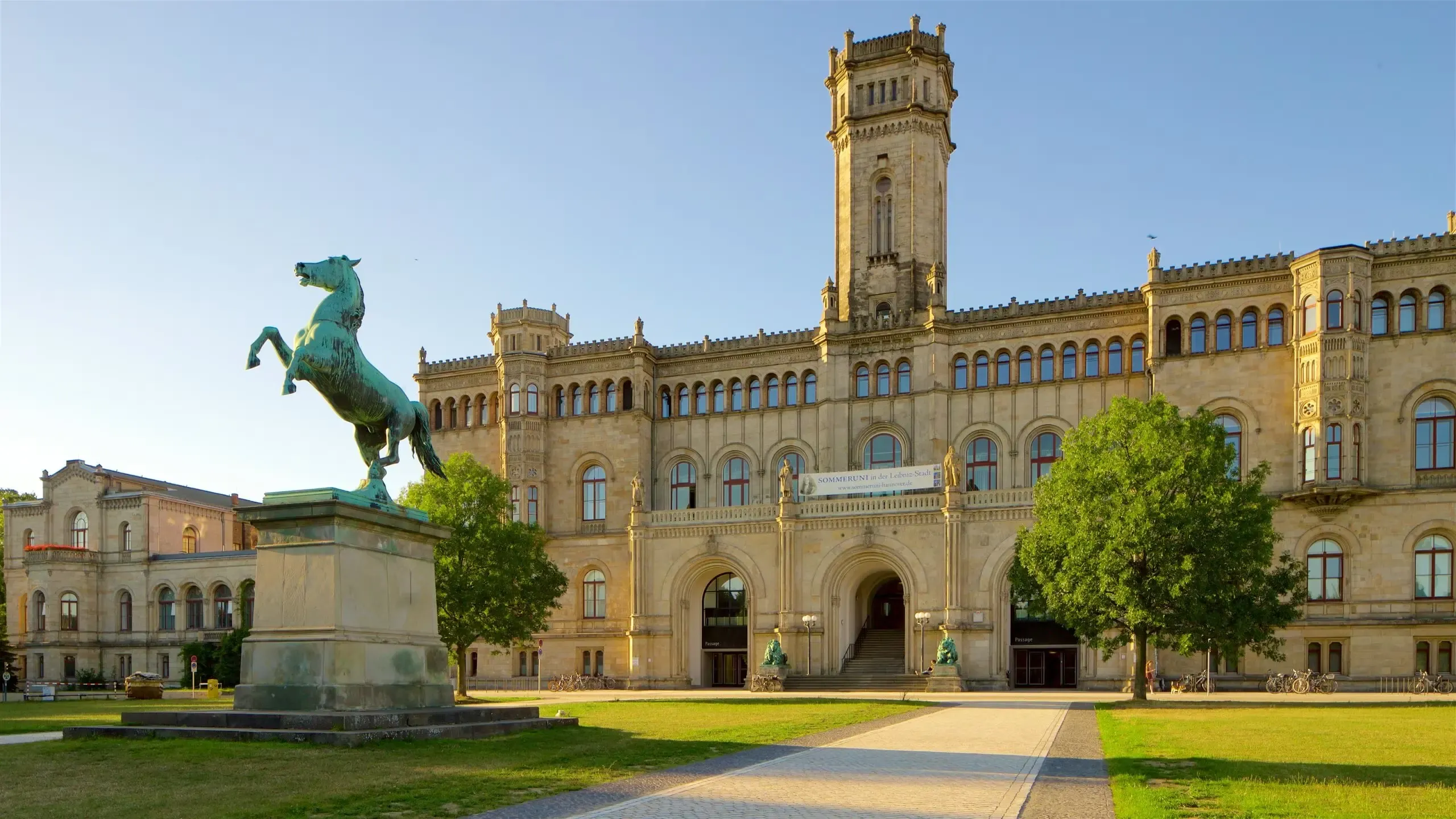 A majestic historic building with a prominent tower and a rearing horse statue in Hannover, Germany.