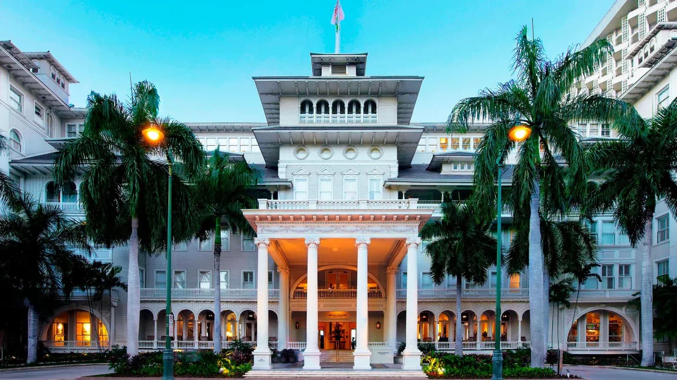 Historic corporate event venue with a grand entrance, white columns, and palm trees in Honolulu, Hawaii.